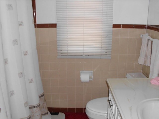 bathroom featuring vanity, tile walls, and toilet