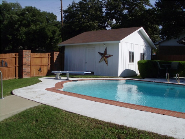 view of swimming pool with an outdoor structure and a diving board