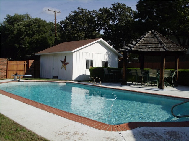 view of pool with a gazebo, an outdoor structure, and a diving board