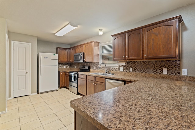 kitchen with appliances with stainless steel finishes, backsplash, light tile patterned floors, and sink