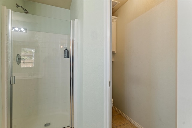 bathroom featuring tile patterned flooring, toilet, and walk in shower