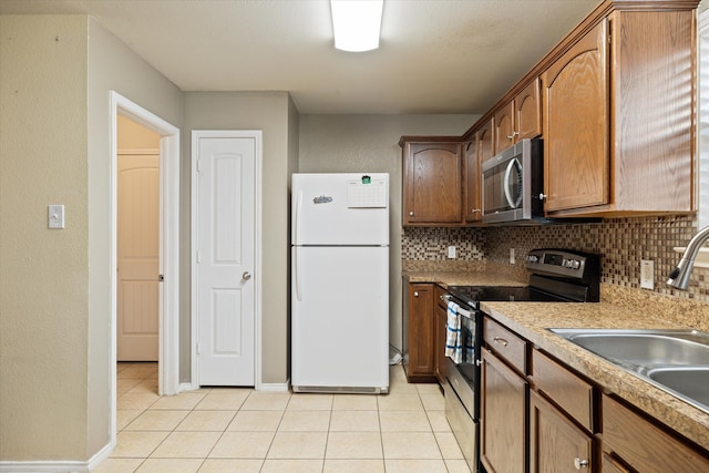 kitchen with light tile patterned flooring, appliances with stainless steel finishes, tasteful backsplash, and sink