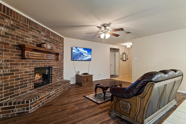 living room with hardwood / wood-style flooring, ceiling fan, and a brick fireplace