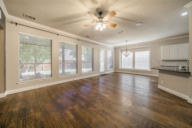 unfurnished living room with dark hardwood / wood-style floors, crown molding, a healthy amount of sunlight, and ceiling fan with notable chandelier