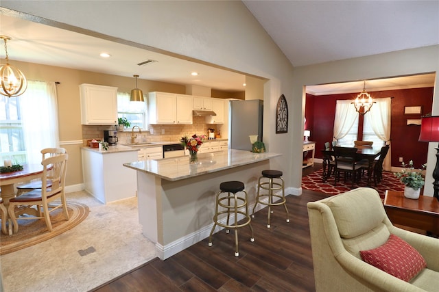 kitchen with hanging light fixtures, white cabinets, a notable chandelier, and stainless steel fridge