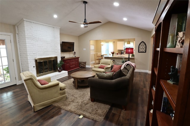 living room featuring ceiling fan, dark hardwood / wood-style flooring, lofted ceiling, and a stone fireplace