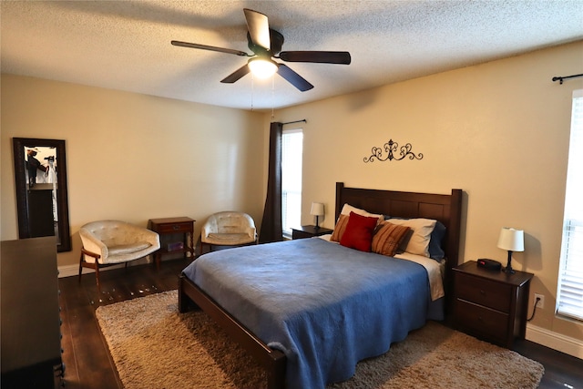 bedroom with ceiling fan, multiple windows, a textured ceiling, and dark hardwood / wood-style floors