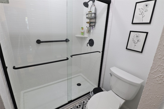 bathroom featuring toilet and a shower with shower door