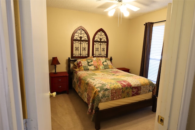 bedroom featuring a textured ceiling, ceiling fan, and light colored carpet