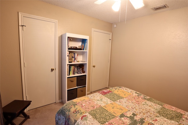 carpeted bedroom featuring ceiling fan and a textured ceiling