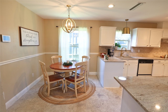 kitchen with decorative light fixtures, stainless steel dishwasher, white cabinets, and light stone countertops