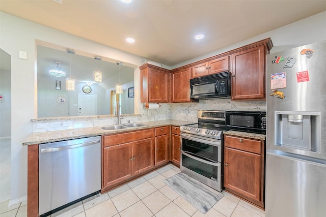 kitchen with sink, light stone countertops, appliances with stainless steel finishes, decorative light fixtures, and kitchen peninsula