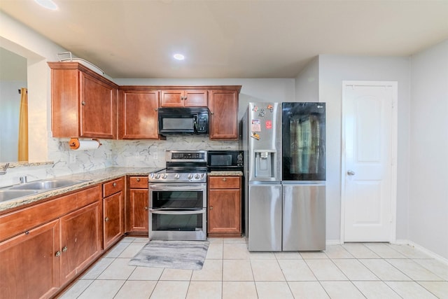 kitchen featuring backsplash, sink, light stone countertops, light tile patterned floors, and appliances with stainless steel finishes