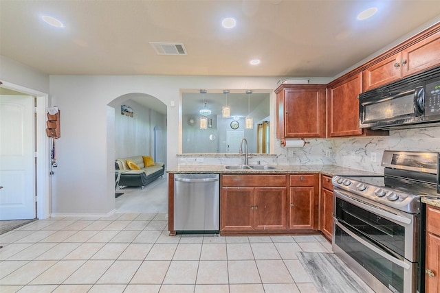 kitchen with pendant lighting, backsplash, sink, light stone counters, and stainless steel appliances