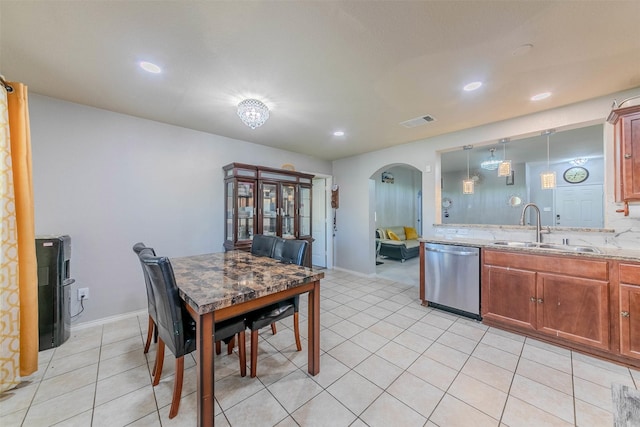 kitchen featuring dishwasher, sink, hanging light fixtures, light stone counters, and light tile patterned floors