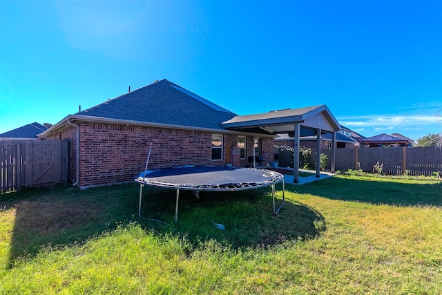 back of property with a yard and a trampoline