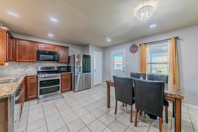 kitchen with an inviting chandelier, sink, decorative backsplash, light tile patterned floors, and appliances with stainless steel finishes