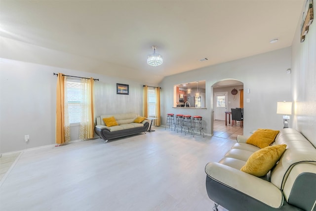 living room with sink, light hardwood / wood-style floors, and an inviting chandelier