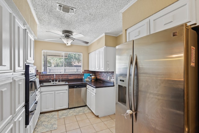 kitchen with white cabinets, sink, light tile patterned floors, appliances with stainless steel finishes, and tasteful backsplash