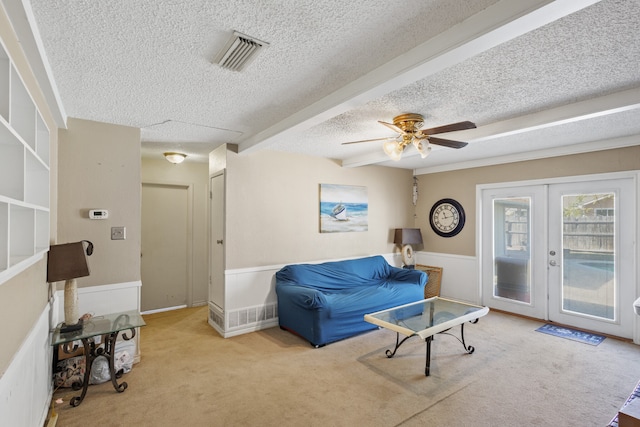 living area with light carpet, french doors, a textured ceiling, ceiling fan, and beam ceiling