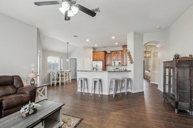 living area with arched walkways, vaulted ceiling, dark wood finished floors, and baseboards