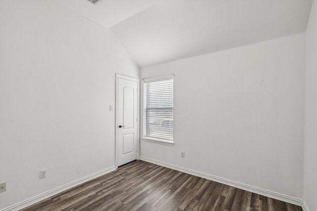 spare room with vaulted ceiling, dark wood finished floors, and baseboards