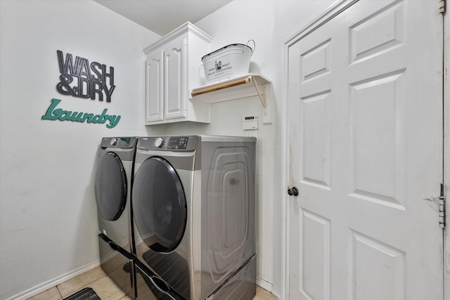 clothes washing area featuring cabinets, light tile patterned floors, and washer and dryer