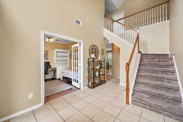 stairway with tile patterned floors, ceiling fan, a towering ceiling, and ornamental molding