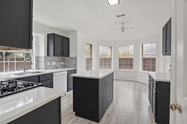 kitchen with dishwasher, ceiling fan, light wood-type flooring, tasteful backsplash, and a kitchen island