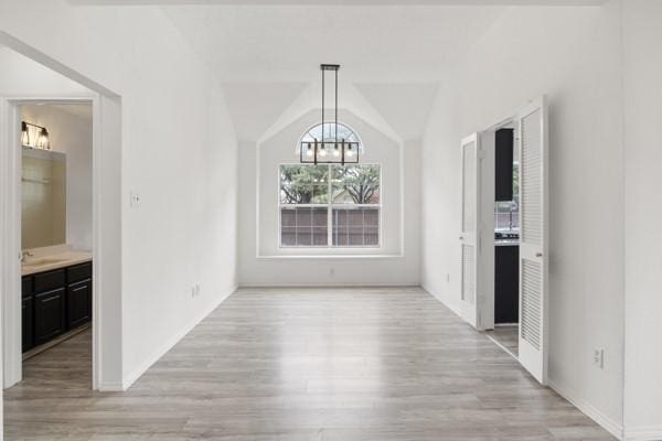 unfurnished dining area with light wood-type flooring, lofted ceiling, and an inviting chandelier