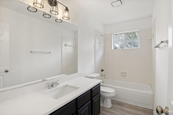 full bathroom with hardwood / wood-style floors, vanity, toilet, and tiled shower / bath