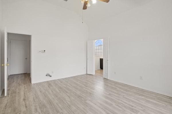 empty room with ceiling fan, high vaulted ceiling, and light hardwood / wood-style floors