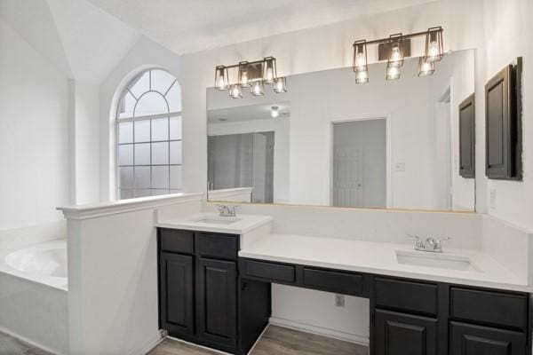 bathroom featuring a bathing tub, hardwood / wood-style floors, vanity, and lofted ceiling