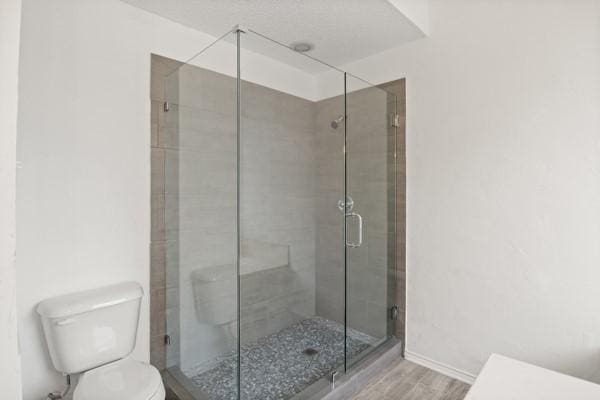 bathroom with wood-type flooring, toilet, and an enclosed shower