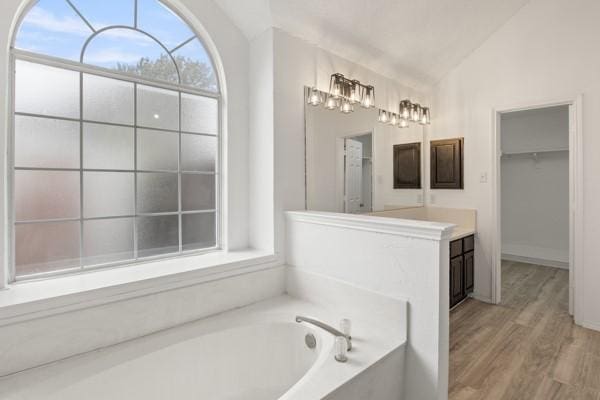 bathroom with a bathing tub, wood-type flooring, and vaulted ceiling