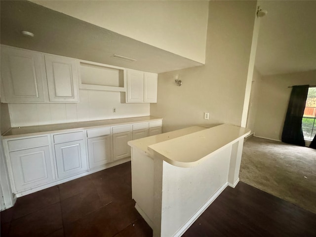 kitchen with white cabinets, dark colored carpet, kitchen peninsula, and a breakfast bar