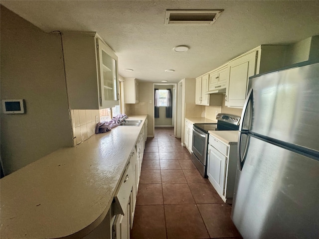 kitchen with custom exhaust hood, stainless steel appliances, dark tile patterned floors, sink, and white cabinets