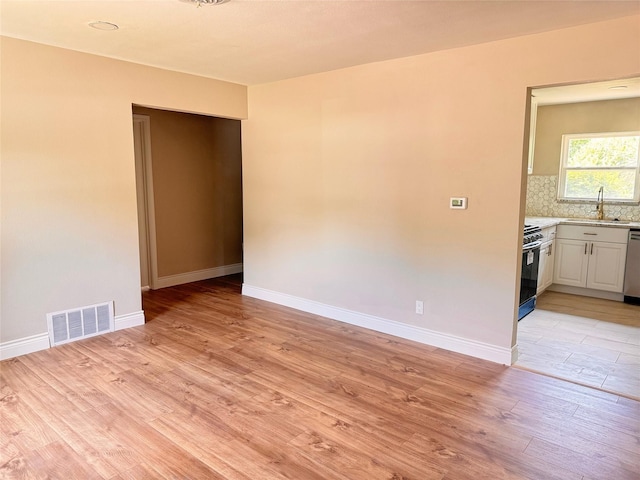 spare room with light wood-type flooring and sink