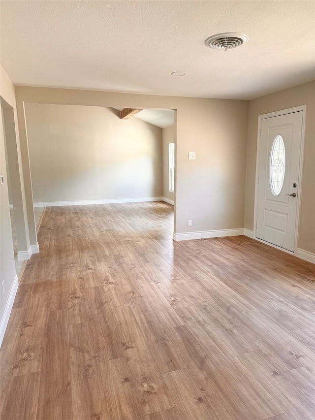 foyer with light wood-type flooring and a textured ceiling