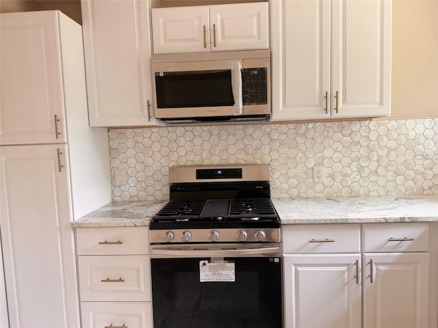 kitchen featuring decorative backsplash, stainless steel appliances, white cabinets, and light stone counters