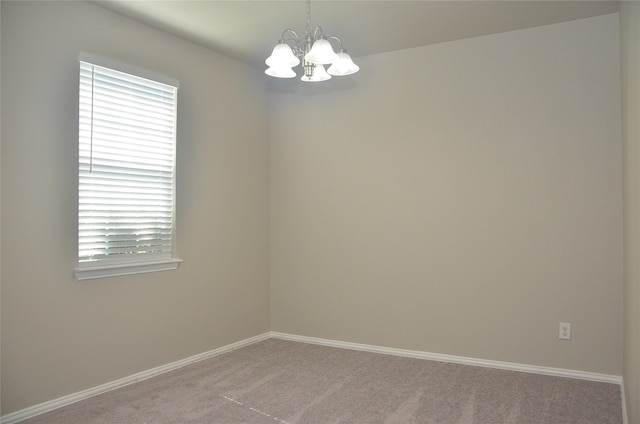 carpeted spare room featuring an inviting chandelier