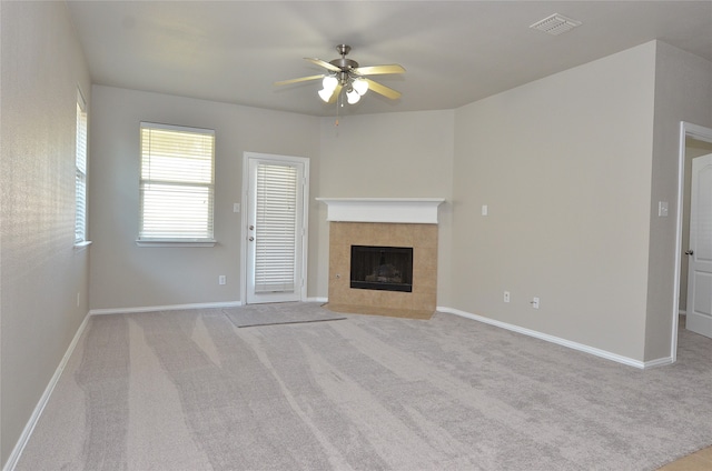 unfurnished living room featuring ceiling fan, light carpet, and a tile fireplace