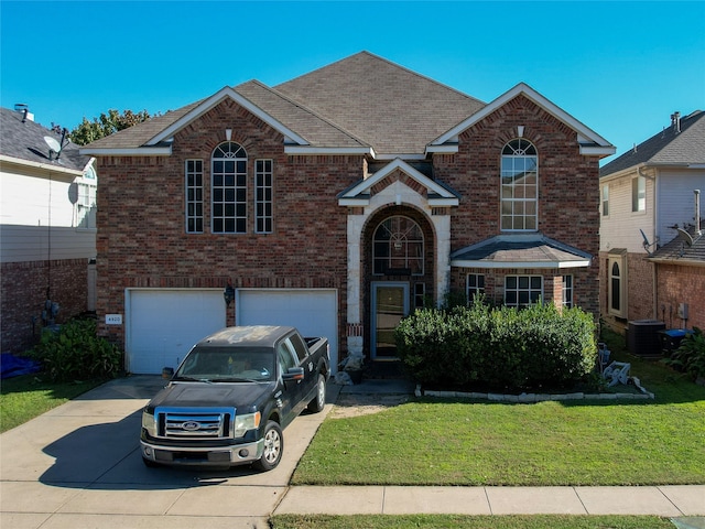 front of property featuring a garage, a front lawn, and central air condition unit