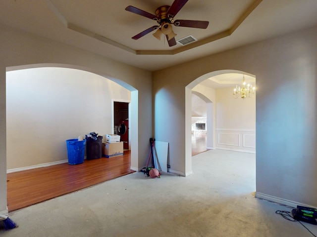 spare room featuring hardwood / wood-style floors, ceiling fan with notable chandelier, washer / clothes dryer, and a raised ceiling