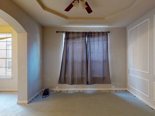 spare room with a tray ceiling, ceiling fan, and light colored carpet