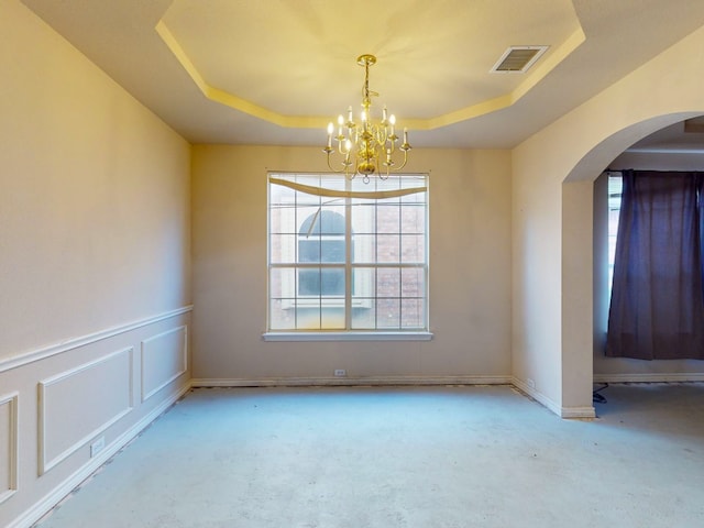 carpeted empty room with a notable chandelier and a tray ceiling