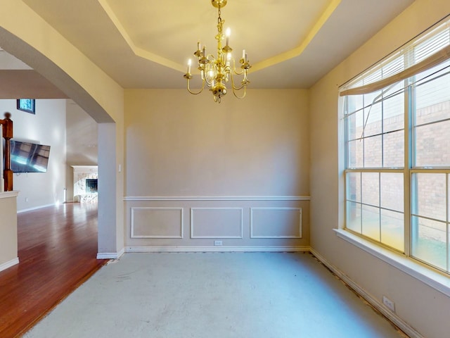 unfurnished room with a raised ceiling, plenty of natural light, and a notable chandelier