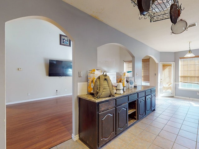 kitchen featuring dark brown cabinetry, hanging light fixtures, and light hardwood / wood-style flooring