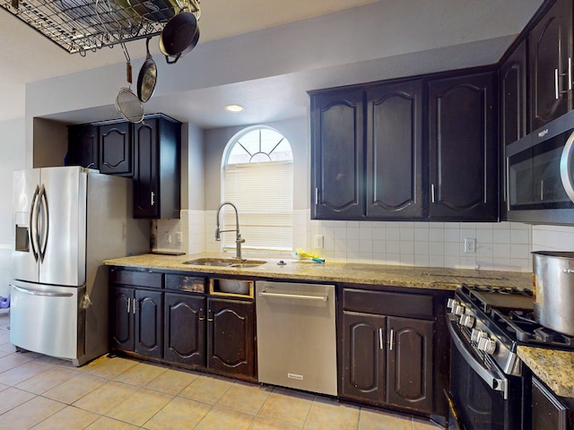 kitchen with sink, decorative backsplash, light stone countertops, light tile patterned floors, and stainless steel appliances