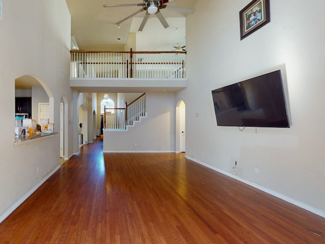 unfurnished living room with ceiling fan, wood-type flooring, and high vaulted ceiling